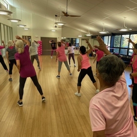 Women doing a zumba class dressed in pink with backs facing the camera.