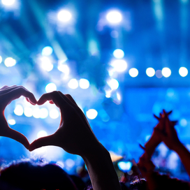Concert background with someone making heart shape with their hands.