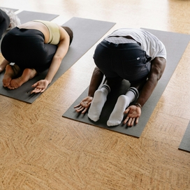 Four people facing down on yoga mats in child's pose.