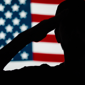 Silhouette of soldier saluting in front of American flag