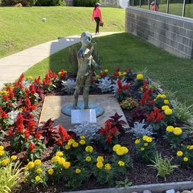 Linwood Center Garden. Statue of a child in a bed of red and yellow flowers